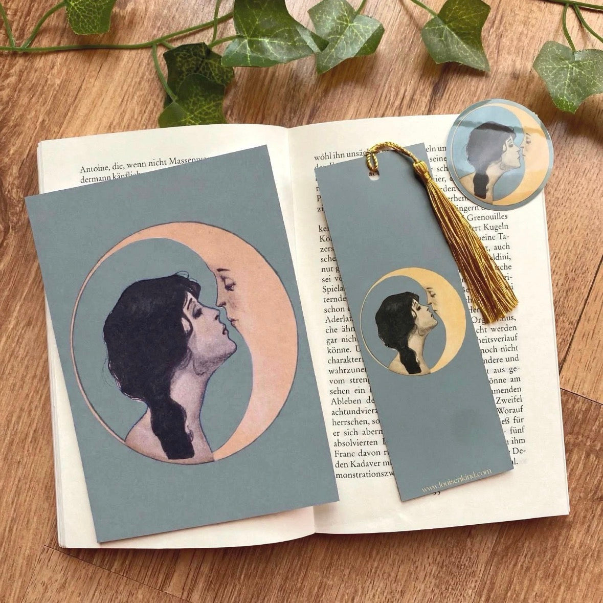 woman kissing moon gift set with postcard bookmark with gold tassel and round vinyl sticker vintage celestial art nouveau bundle on wooden table