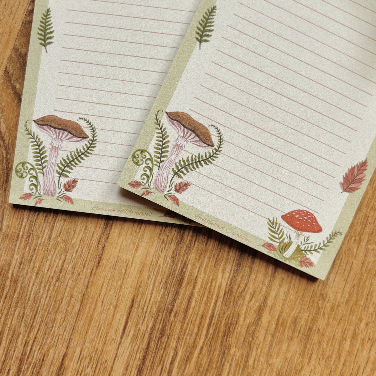 mushroom illustrated A7 notepad with 25 lined sheets amanita and chestnut mushrooms with ferns and autumn leaves notes sage green border on wooden table