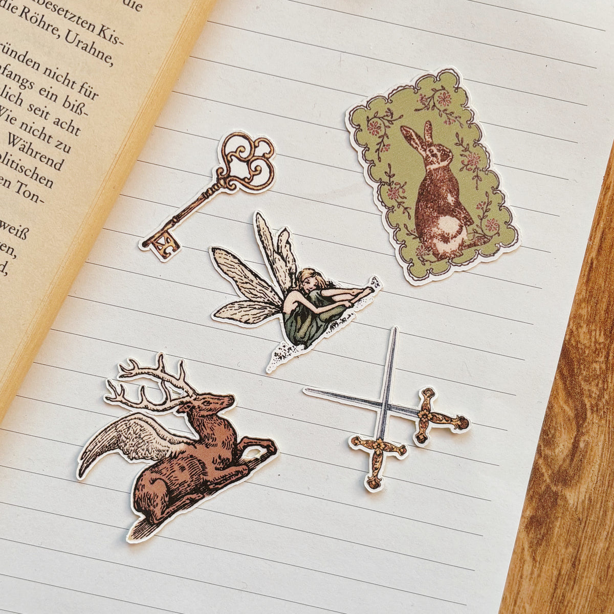 fairy themed sticker set 5 vintage fantasy stickers with fairy with wings winged deer bunny rabbit in sage frame skeleton key and crossed swords on a notebook page